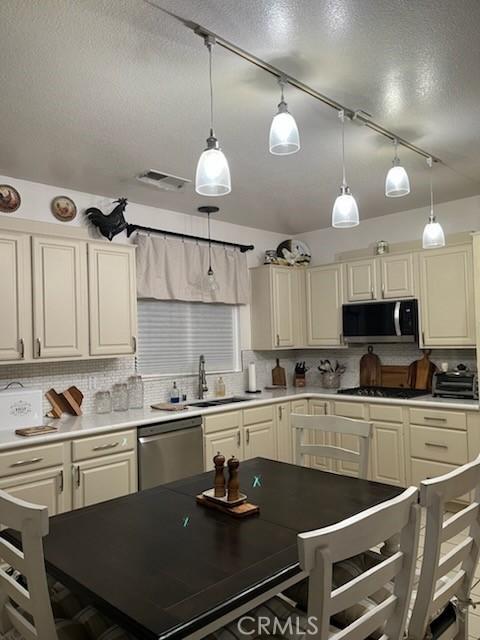 kitchen with light countertops, visible vents, backsplash, appliances with stainless steel finishes, and a sink