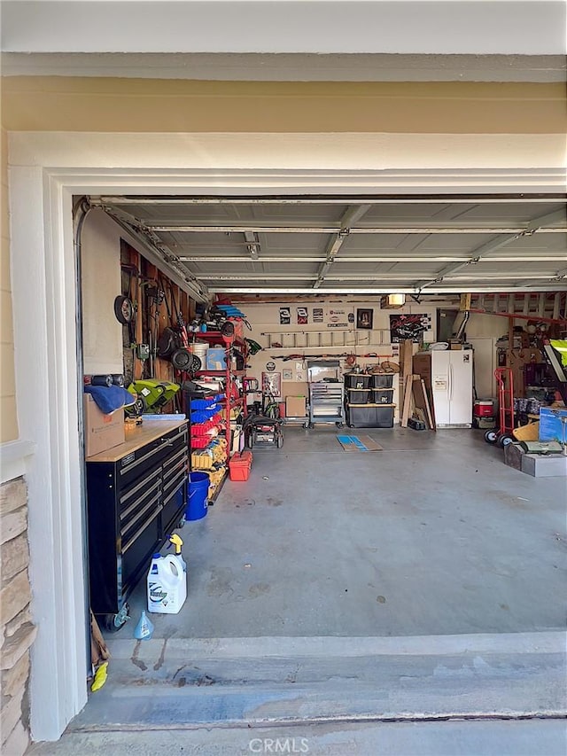 garage featuring white refrigerator with ice dispenser and a workshop area