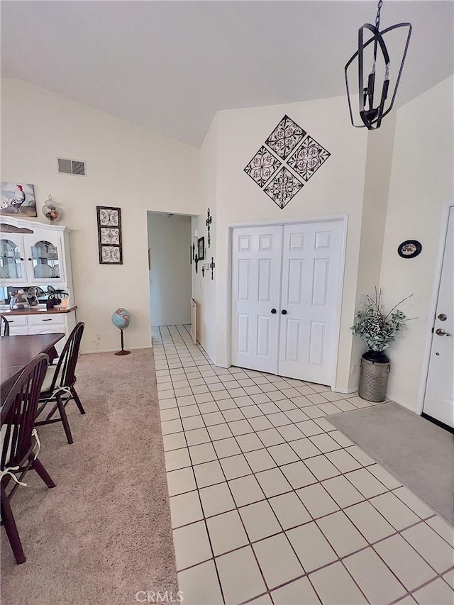 entryway featuring high vaulted ceiling, visible vents, and light colored carpet