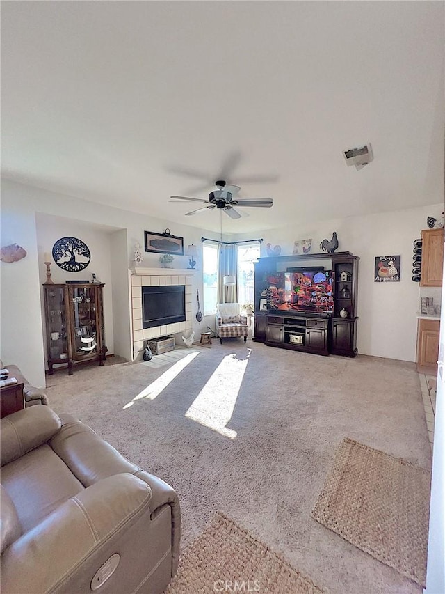 carpeted living room featuring a fireplace and ceiling fan