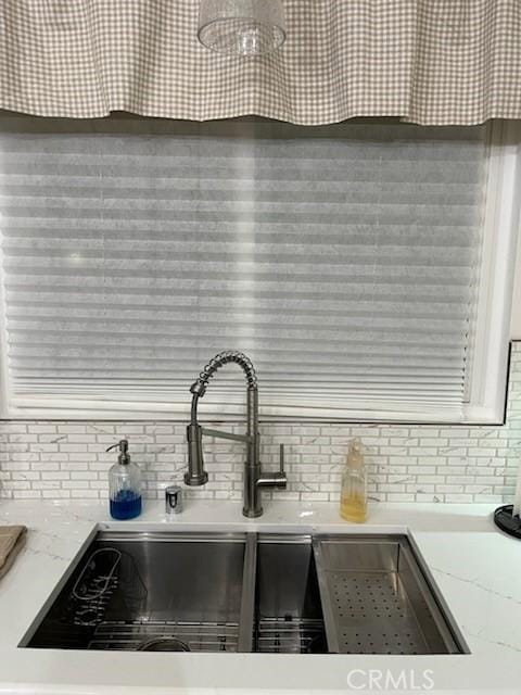 interior details featuring light stone countertops, decorative backsplash, and a sink