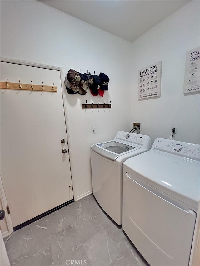 laundry room featuring marble finish floor, laundry area, washing machine and dryer, and baseboards