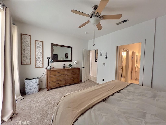 bedroom featuring a ceiling fan, ensuite bath, visible vents, and light colored carpet