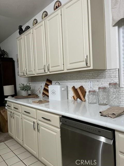 kitchen with light tile patterned floors, light countertops, backsplash, white cabinetry, and dishwasher