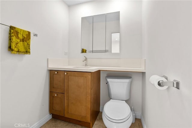 bathroom featuring toilet, baseboards, and vanity