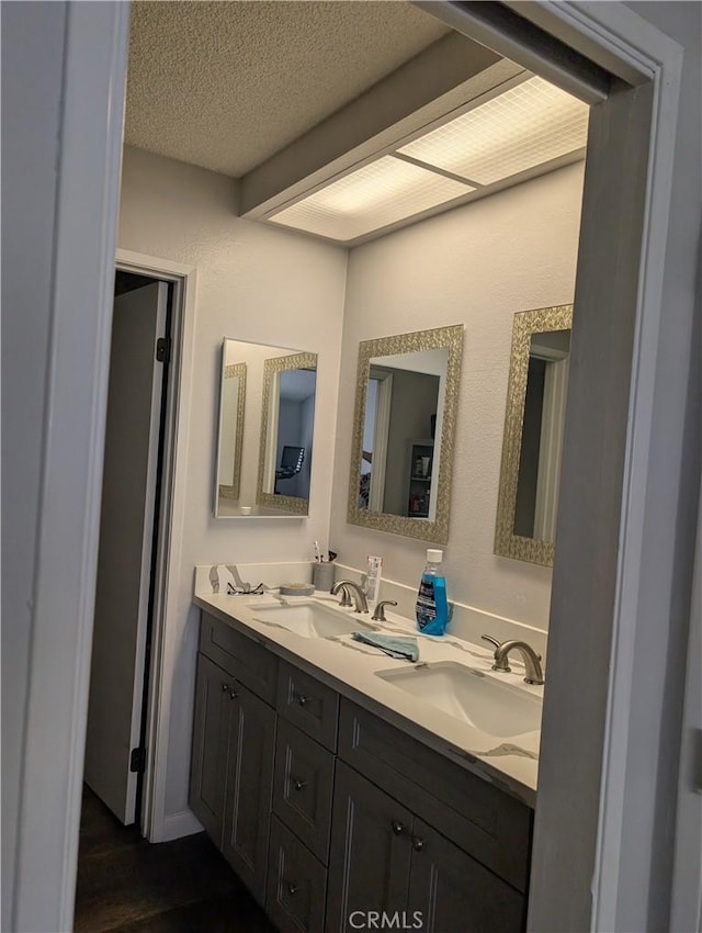 bathroom featuring a sink, a textured ceiling, and double vanity