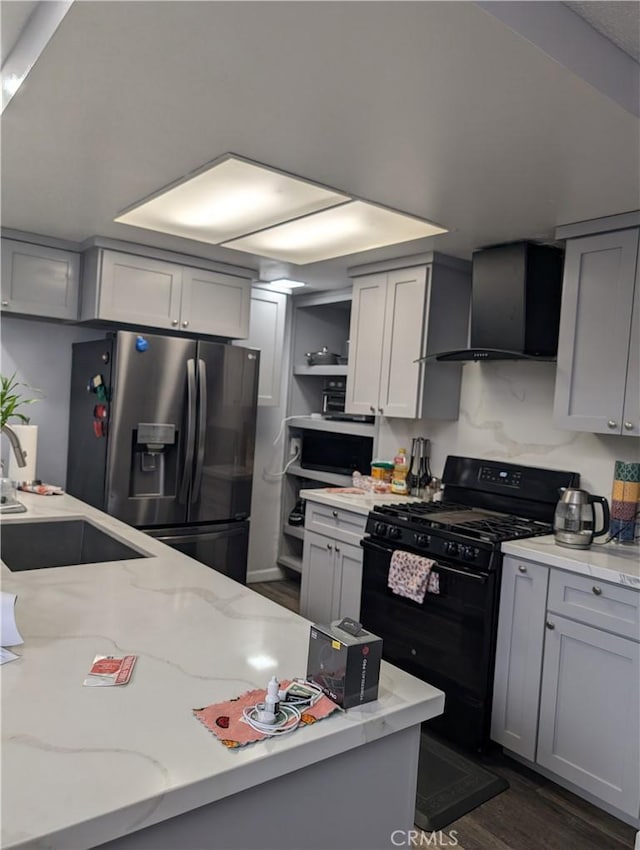 kitchen featuring stainless steel fridge, wall chimney range hood, open shelves, a sink, and gas stove