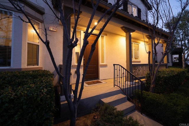 property entrance featuring covered porch and stucco siding