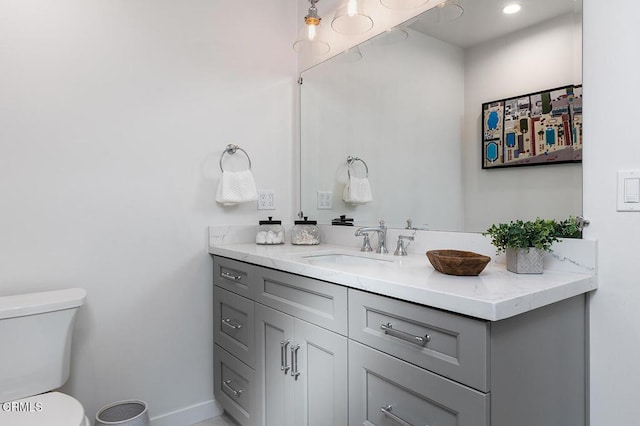 bathroom featuring toilet, baseboards, and vanity