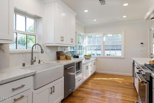 kitchen featuring stainless steel appliances, a sink, visible vents, backsplash, and crown molding