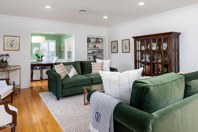 living area with built in shelves, ornamental molding, wood-type flooring, and visible vents