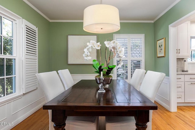 dining space with crown molding and light wood-style floors