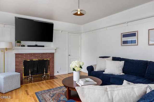 living room with a brick fireplace, wood finished floors, and crown molding