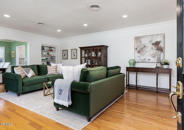 living room featuring light wood-type flooring, visible vents, and crown molding