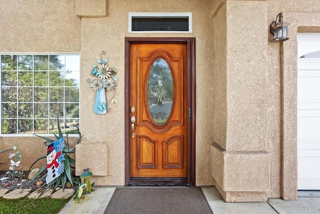 doorway to property with a garage and stucco siding