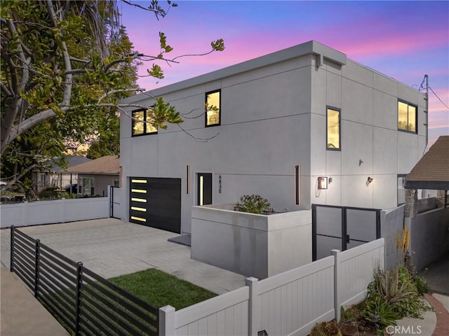 view of front of property featuring a fenced front yard, stucco siding, driveway, and an attached garage