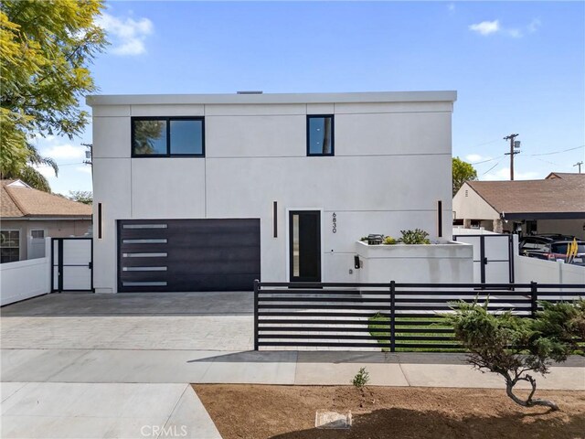 modern home with an attached garage, a fenced front yard, decorative driveway, and stucco siding