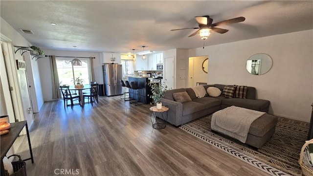 living area featuring dark wood-style floors, visible vents, and a ceiling fan