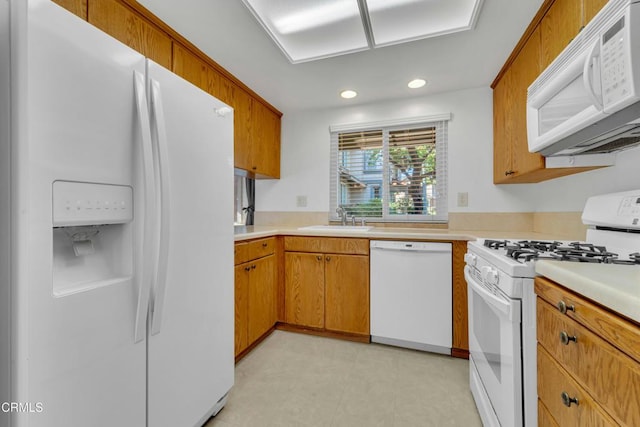 kitchen with white appliances, light countertops, a sink, and light floors