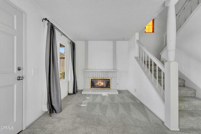 living room with carpet floors, stairway, a fireplace, and a textured ceiling