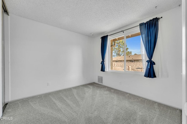 carpeted empty room featuring visible vents and a textured ceiling