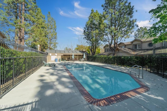 community pool featuring a fenced backyard and a patio