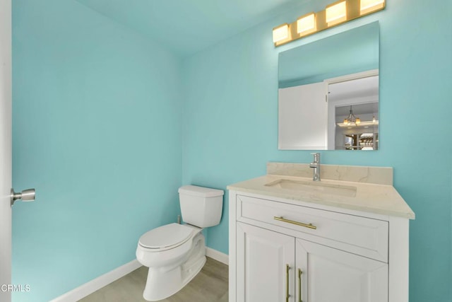 bathroom featuring baseboards, vanity, toilet, and wood finished floors