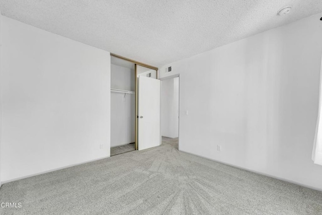 unfurnished bedroom with a textured ceiling, a closet, visible vents, and carpet flooring