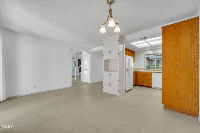 kitchen featuring arched walkways, white appliances, visible vents, light countertops, and light floors