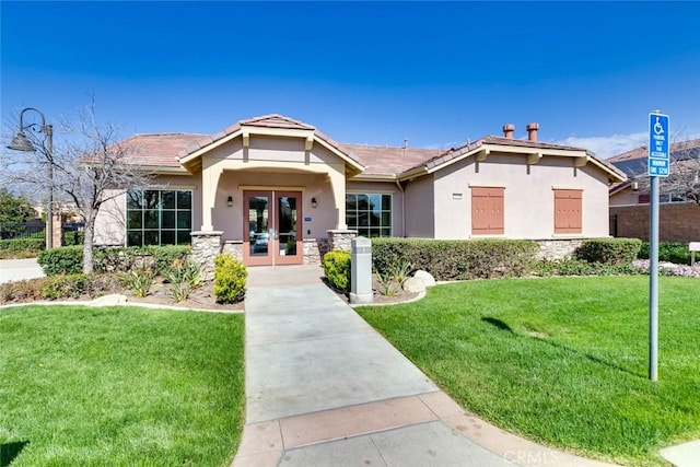 view of front of house featuring stone siding, a tile roof, french doors, a front lawn, and stucco siding