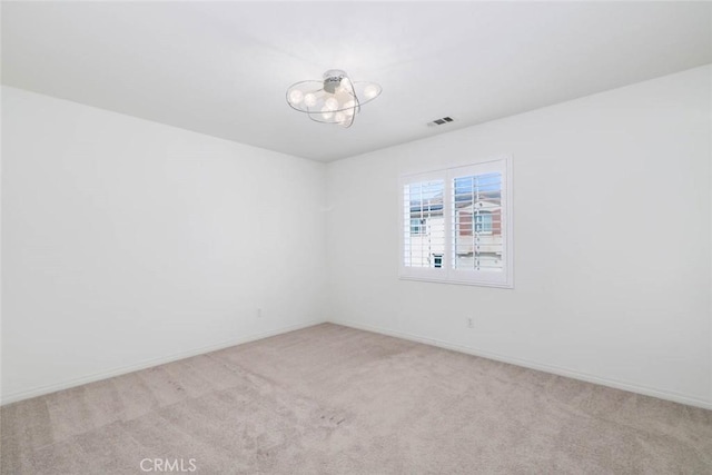 spare room featuring baseboards, visible vents, and light colored carpet