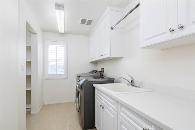 washroom featuring a sink, visible vents, baseboards, cabinet space, and washer and clothes dryer