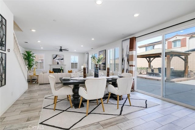 dining space featuring light wood-style floors, ceiling fan, a fireplace, and recessed lighting