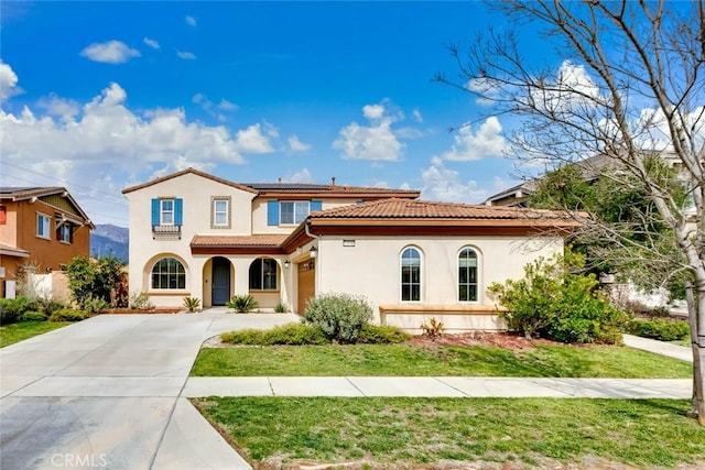 mediterranean / spanish-style home featuring stucco siding, roof mounted solar panels, driveway, a tiled roof, and a front lawn