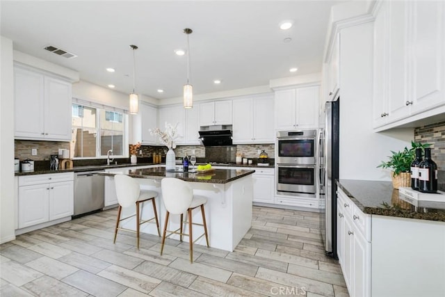 kitchen with appliances with stainless steel finishes, a center island, visible vents, and white cabinetry