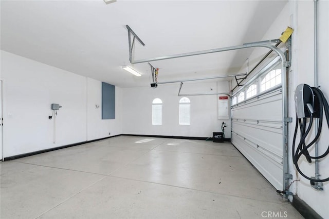 garage featuring baseboards, electric panel, and a garage door opener