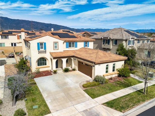 mediterranean / spanish-style home featuring driveway, a tiled roof, a mountain view, and stucco siding