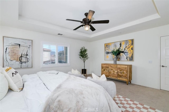 bedroom featuring carpet, a raised ceiling, visible vents, and ceiling fan