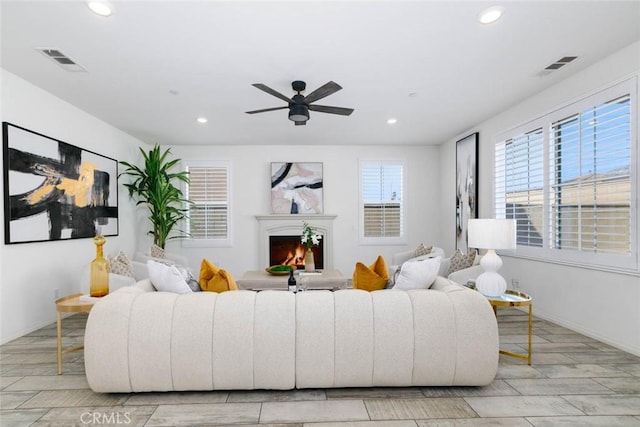 living room featuring a lit fireplace, visible vents, and recessed lighting