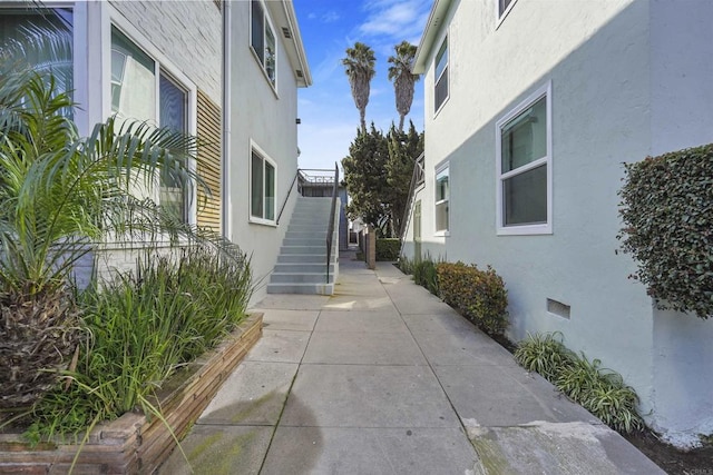 view of property exterior with stairs, crawl space, and stucco siding