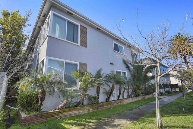 view of side of home featuring a yard and stucco siding