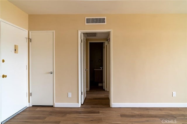 unfurnished room featuring wood finished floors, visible vents, and baseboards