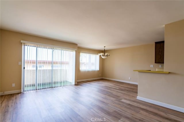 interior space featuring baseboards, a notable chandelier, and wood finished floors