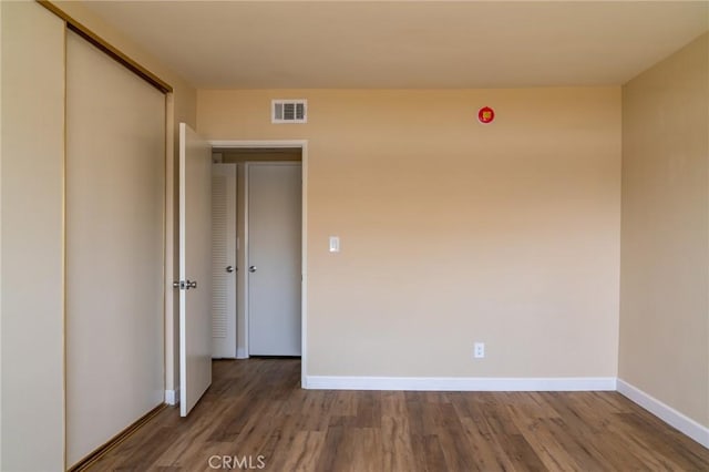 empty room with baseboards, visible vents, and wood finished floors