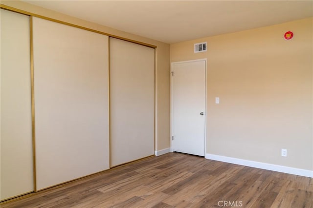 unfurnished bedroom featuring light wood-type flooring, visible vents, and a closet