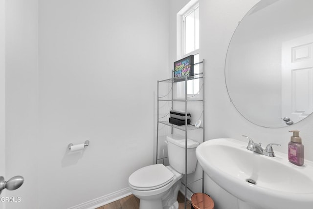 bathroom with wood finished floors, a sink, toilet, and baseboards