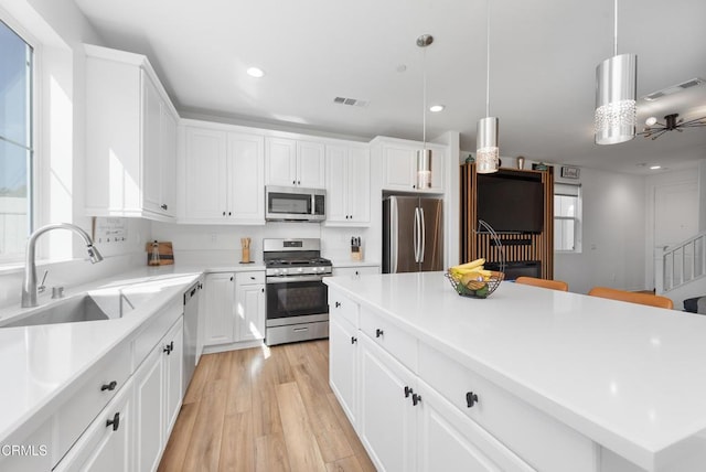 kitchen featuring visible vents, white cabinets, appliances with stainless steel finishes, light wood-style floors, and a sink