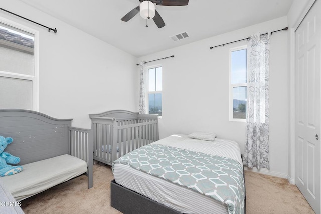 carpeted bedroom featuring ceiling fan, a closet, and visible vents