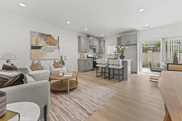 living room featuring light wood finished floors, visible vents, and recessed lighting