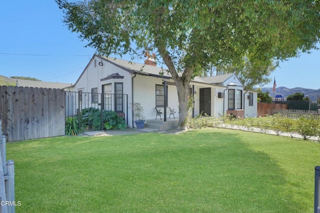 view of front of house with a front lawn, a chimney, fence, and stucco siding